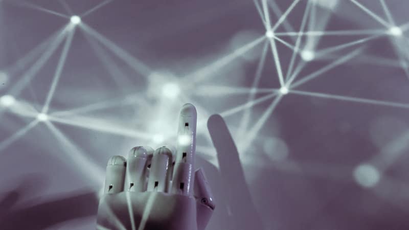 Robotic hand reaching toward a network of connected nodes