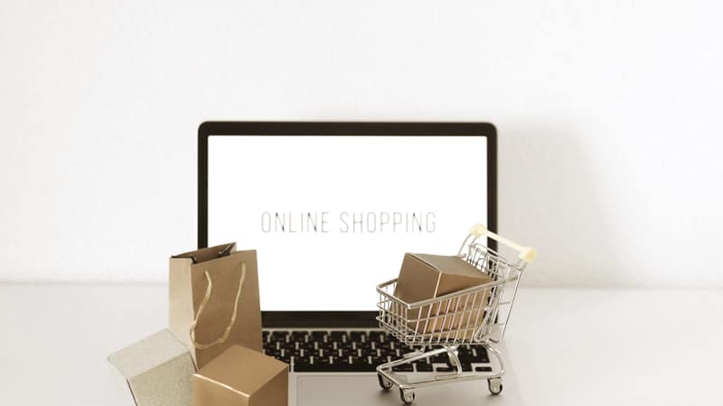 Laptop beside a miniature shopping trolley and parcels